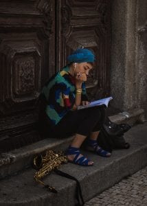 teach abroad Search Associates ANZ a musician sitting, reading a book with her saxophone played down next to her