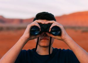 recruiting in international schools Search Associates ANZ a man in the desert looking through binoculars 