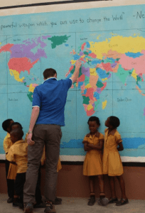 International school recruitment agencies Search Associates ANZ teacher with his class pointing at a map of the world